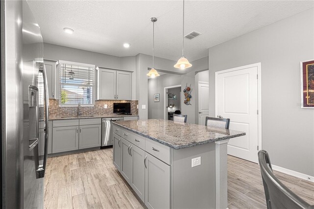 kitchen with light wood-type flooring, visible vents, stainless steel appliances, and gray cabinetry