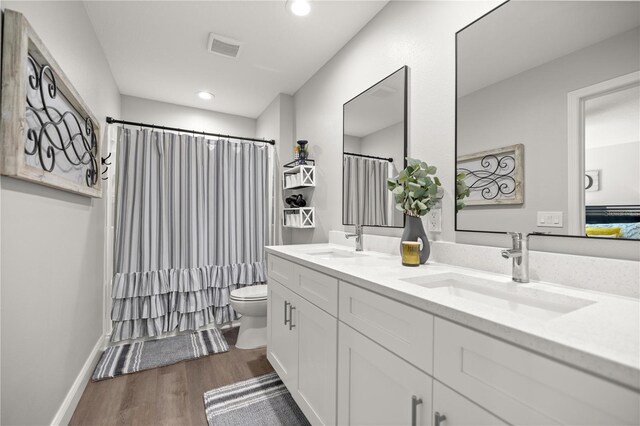 77 Locust Dr, Ocala, FL 34472 - bathroom with toilet, wood finished floors, double vanity, recessed lighting, and a shower with shower curtain