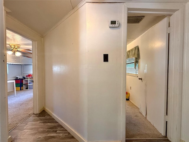 hall with crown molding, wood finished floors, baseboards, and carpet floors