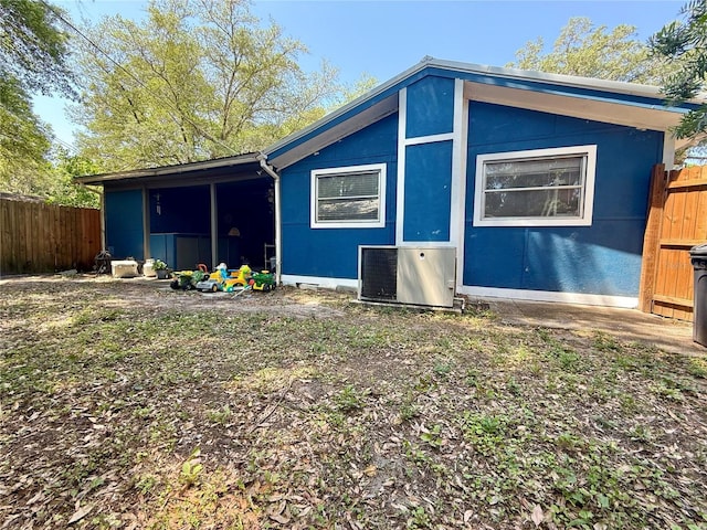 rear view of house with central AC unit and fence