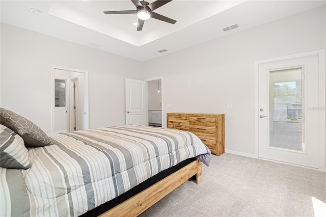 carpeted bedroom with a tray ceiling and ceiling fan