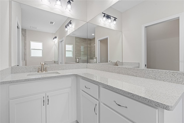 bathroom featuring a shower with door and double vanity