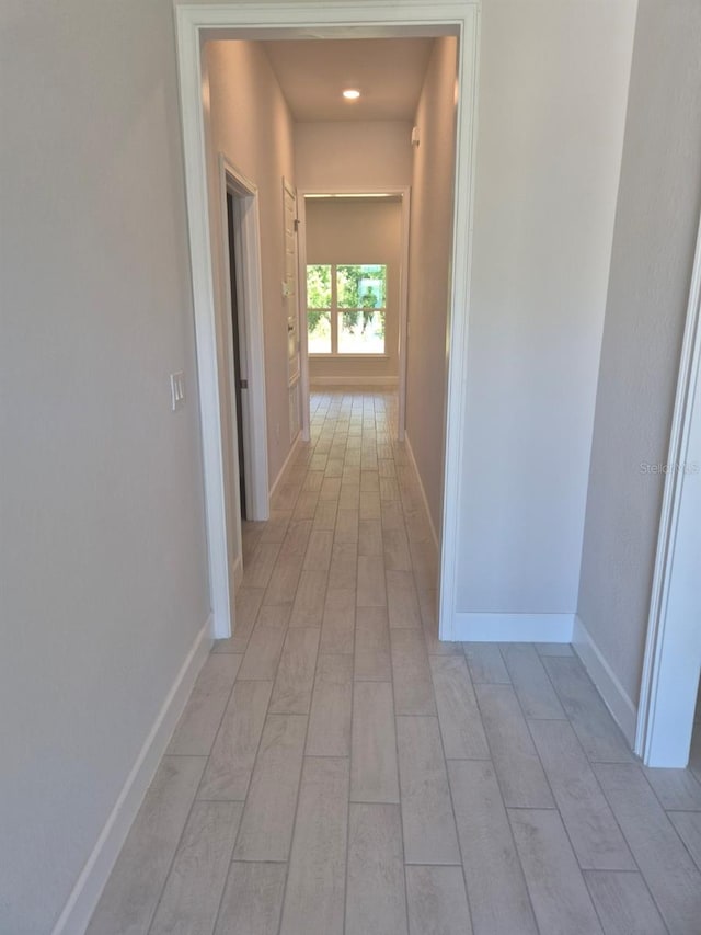 hallway with light wood-style flooring and baseboards