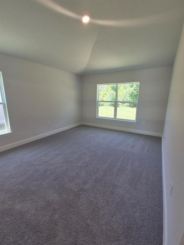 empty room with baseboards and dark colored carpet