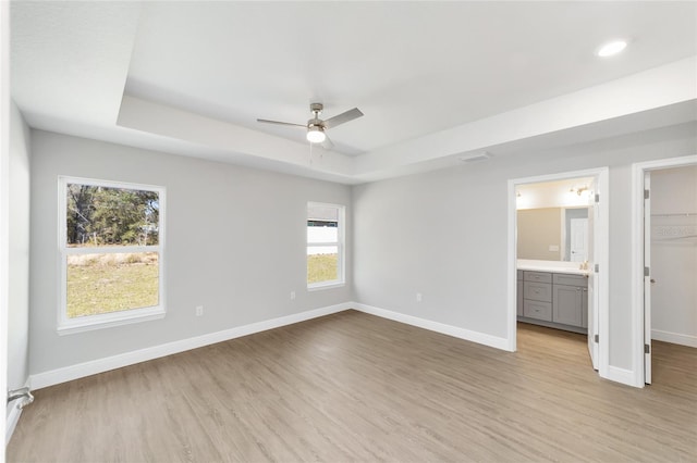 10374 SE 126th Ln, Belleview, FL 34420 - unfurnished bedroom with baseboards, a spacious closet, light wood finished floors, and a raised ceiling
