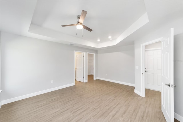 10374 SE 126th Ln, Belleview, FL 34420 - unfurnished bedroom with light wood-type flooring, a raised ceiling, baseboards, a spacious closet, and recessed lighting