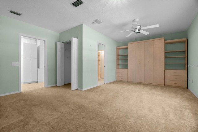 unfurnished bedroom featuring ceiling fan, visible vents, baseboards, and light carpet