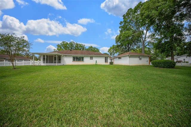 back of house featuring stucco siding, a yard, a sunroom, and fence