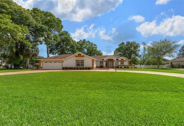 view of front of property featuring a front lawn, driveway, an attached garage, fence, and stucco siding