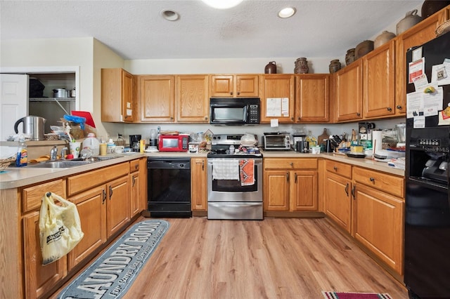 15426 SW 14th Avenue Rd, Ocala, FL 34473 - kitchen with a sink, light countertops, a textured ceiling, black appliances, and light wood finished floors