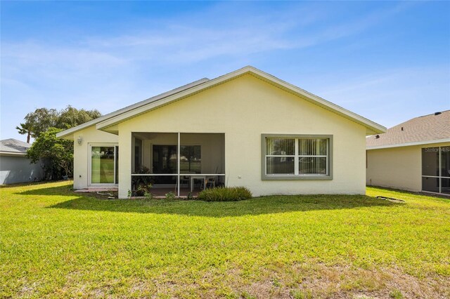 15426 SW 14th Avenue Rd, Ocala, FL 34473 - back of house featuring stucco siding, a sunroom, and a lawn