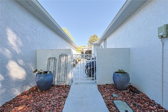 exterior space with a gate and stucco siding