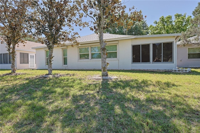rear view of house featuring stucco siding and a lawn