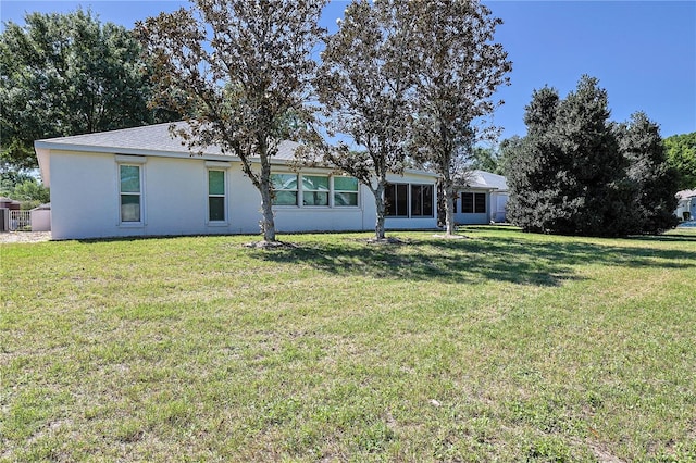 rear view of house with a yard and stucco siding
