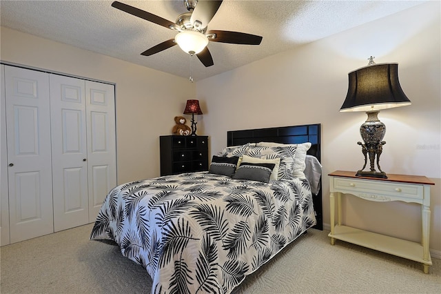 bedroom with a textured ceiling, a closet, light colored carpet, and ceiling fan