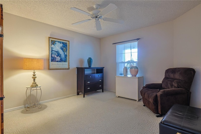 living area featuring carpet floors, a textured ceiling, and ceiling fan