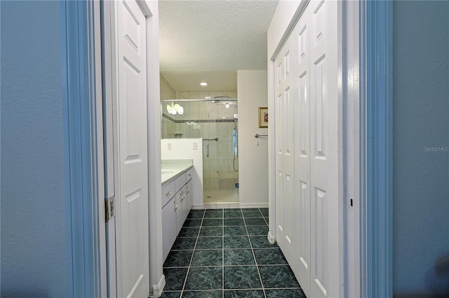 bathroom with tile patterned floors, vanity, a stall shower, and a textured ceiling