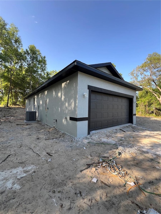 1581 W Saint Elizabeth Pl, Citrus Springs, FL 34434 - view of property exterior with a garage, stucco siding, and central AC unit