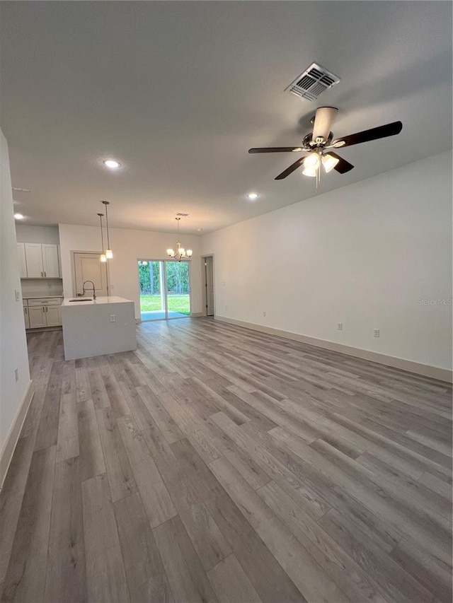 1581 W Saint Elizabeth Pl, Citrus Springs, FL 34434 - unfurnished living room with visible vents, baseboards, recessed lighting, wood finished floors, and ceiling fan with notable chandelier