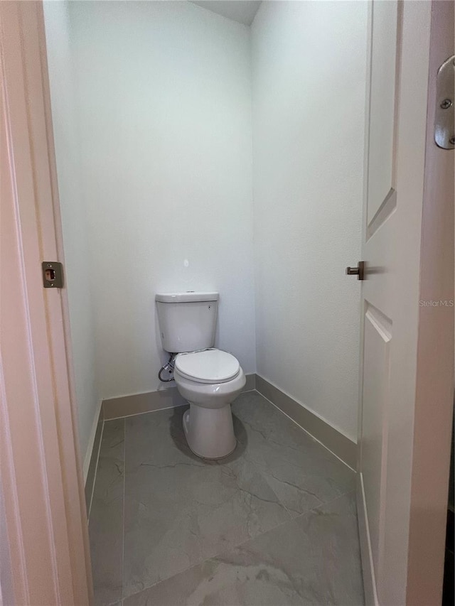 1581 W Saint Elizabeth Pl, Citrus Springs, FL 34434 - bathroom featuring toilet, marble finish floor, and baseboards