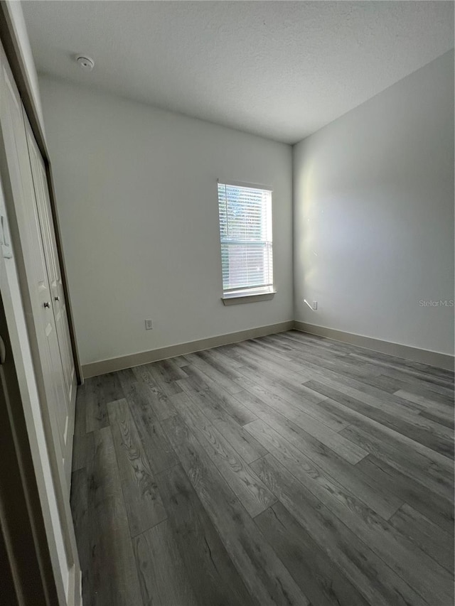 1581 W Saint Elizabeth Pl, Citrus Springs, FL 34434 - unfurnished bedroom with a textured ceiling, wood finished floors, and baseboards