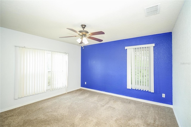 carpeted empty room featuring baseboards, visible vents, and ceiling fan