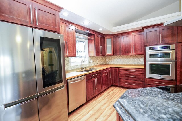 kitchen featuring light wood-type flooring, stainless steel appliances, reddish brown cabinets, and a sink