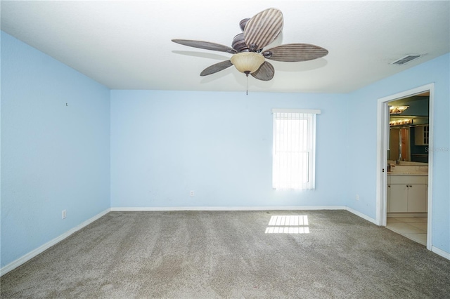 carpeted empty room featuring baseboards, visible vents, and ceiling fan
