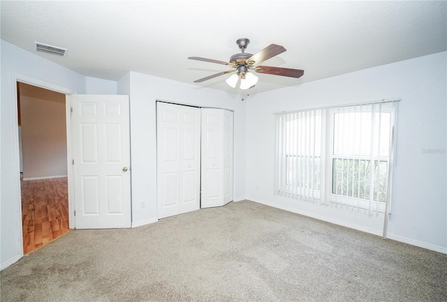 unfurnished bedroom with carpet flooring, a closet, ceiling fan, visible vents, and baseboards