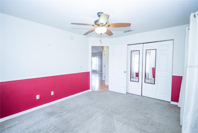 unfurnished bedroom with a closet, a ceiling fan, visible vents, carpet, and baseboards