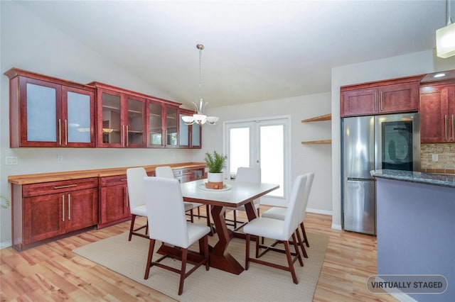 dining space featuring an inviting chandelier, vaulted ceiling, light wood-style flooring, baseboards, and french doors