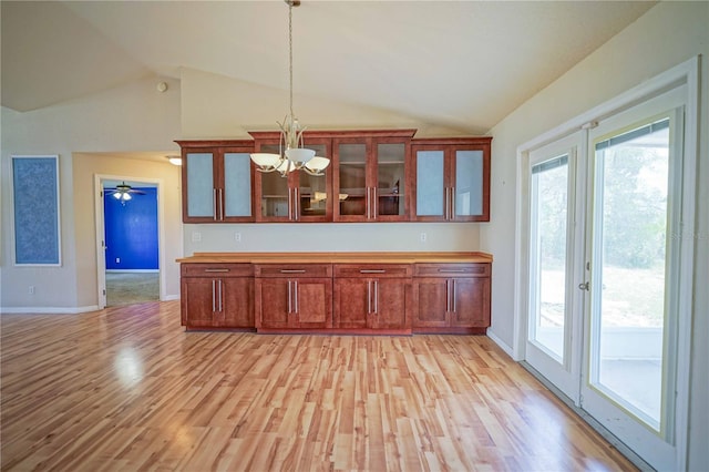 2730 SW 162nd Street Rd, Ocala, FL 34473 - kitchen featuring lofted ceiling, a chandelier, pendant lighting, light wood finished floors, and glass insert cabinets