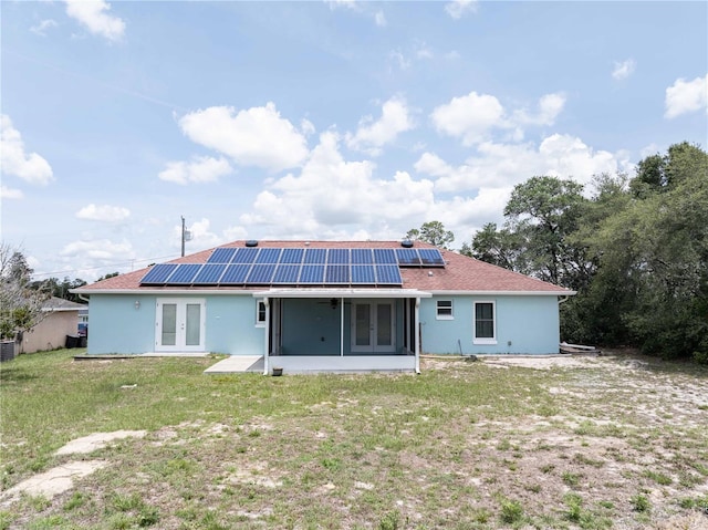 2730 SW 162nd Street Rd, Ocala, FL 34473 - back of house featuring french doors, a sunroom, a lawn, solar panels, and stucco siding