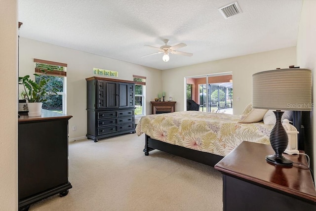 bedroom with a ceiling fan, a textured ceiling, light carpet, access to outside, and visible vents