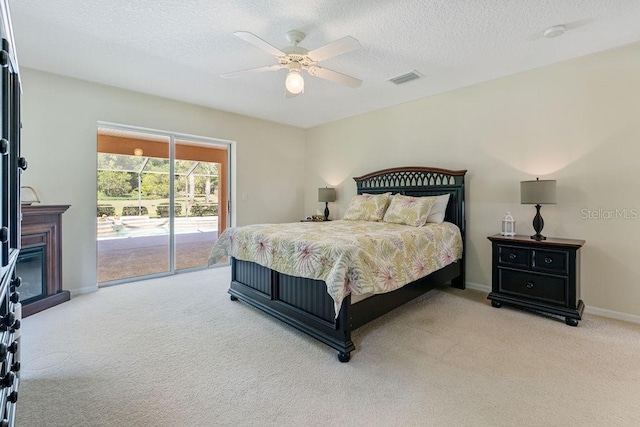 bedroom featuring a textured ceiling, access to exterior, a ceiling fan, and light colored carpet