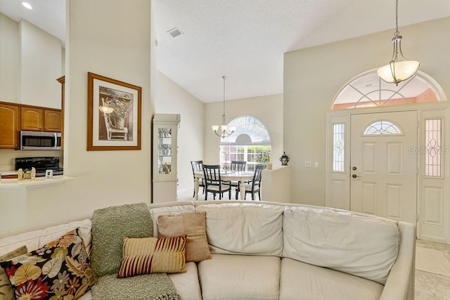 entrance foyer with visible vents, high vaulted ceiling, and an inviting chandelier