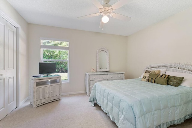 bedroom with ceiling fan, baseboards, a textured ceiling, and light colored carpet