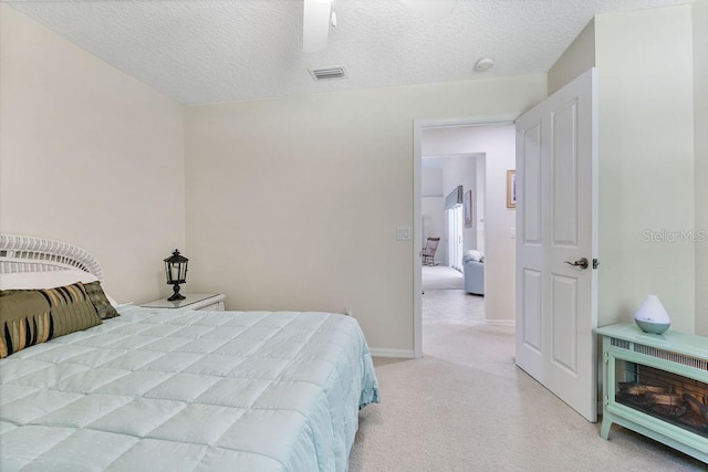bedroom featuring a ceiling fan, a textured ceiling, light carpet, baseboards, and visible vents