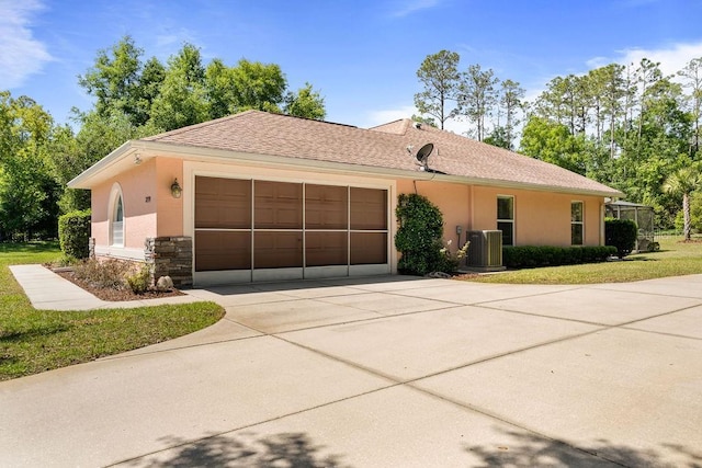 ranch-style house featuring central AC, driveway, stone siding, an attached garage, and stucco siding