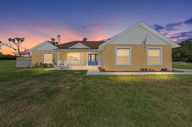 9950 NW 11th Ter, Ocala, FL 34475 - back of house at dusk featuring a lawn, stucco siding, and french doors