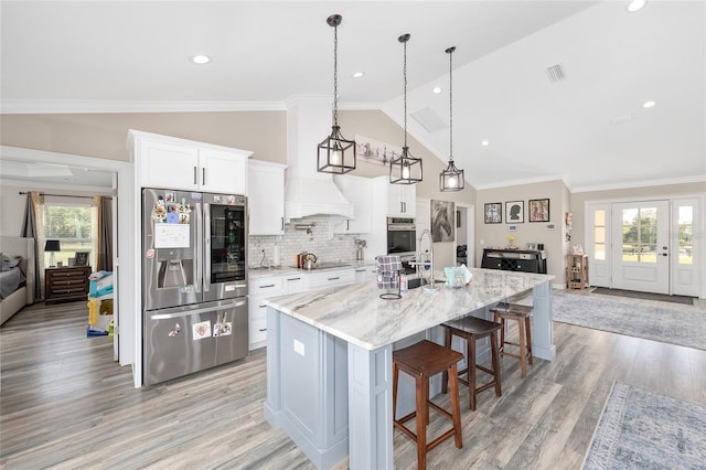 9950 NW 11th Ter, Ocala, FL 34475 - kitchen with stainless steel appliances, lofted ceiling, light wood-type flooring, white cabinets, and a kitchen breakfast bar