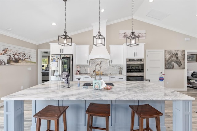 9950 NW 11th Ter, Ocala, FL 34475 - kitchen featuring stainless steel appliances, a spacious island, a breakfast bar, light wood-style flooring, and white cabinetry