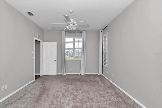 carpeted spare room featuring visible vents, baseboards, and a ceiling fan