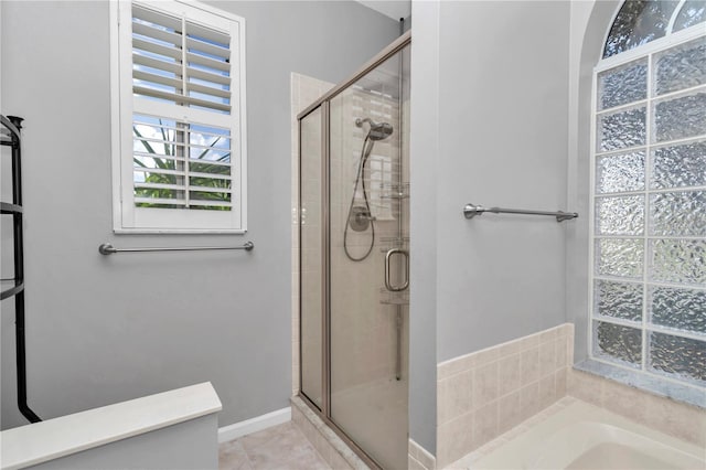 full bathroom featuring a bath, a stall shower, and baseboards