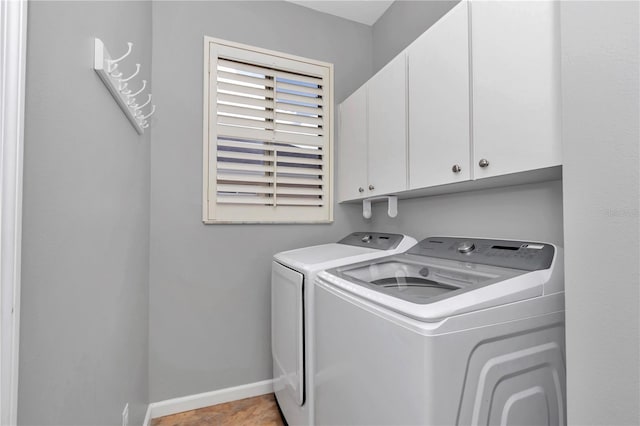 washroom with washing machine and clothes dryer, baseboards, and cabinet space