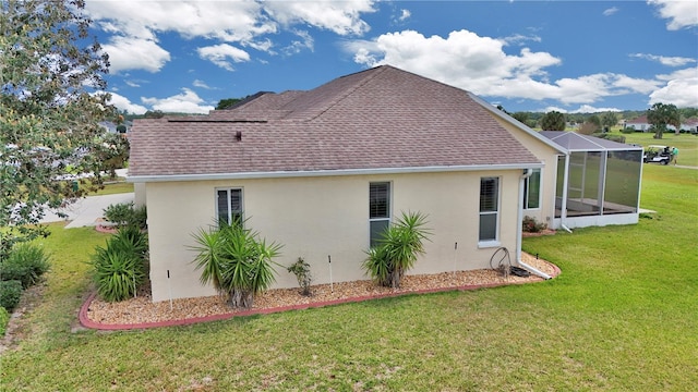 view of side of home featuring roof with shingles, a lanai, a lawn, and stucco siding