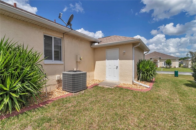 view of exterior entry featuring stucco siding, a lawn, and central air condition unit