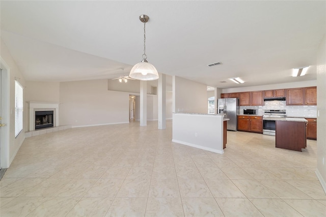 9896 SW 56th Ct, Ocala, FL 34476 - kitchen with a tiled fireplace, light countertops, hanging light fixtures, open floor plan, and stainless steel appliances