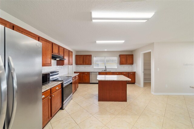 9896 SW 56th Ct, Ocala, FL 34476 - kitchen with appliances with stainless steel finishes, a center island, under cabinet range hood, decorative backsplash, and a sink