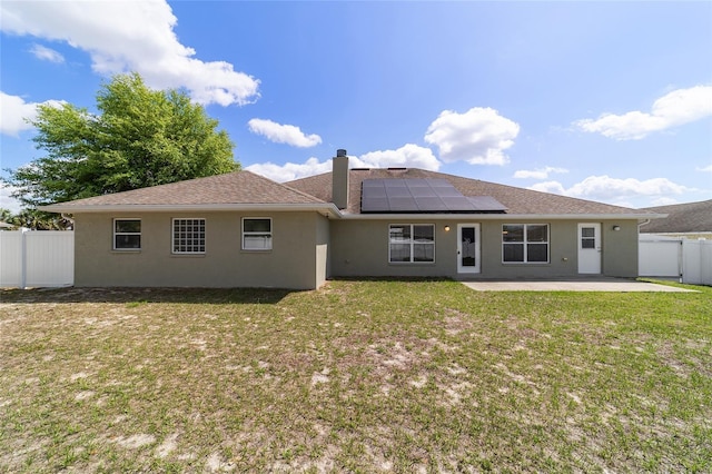 9896 SW 56th Ct, Ocala, FL 34476 - rear view of house featuring roof mounted solar panels, a fenced backyard, stucco siding, a lawn, and a patio area